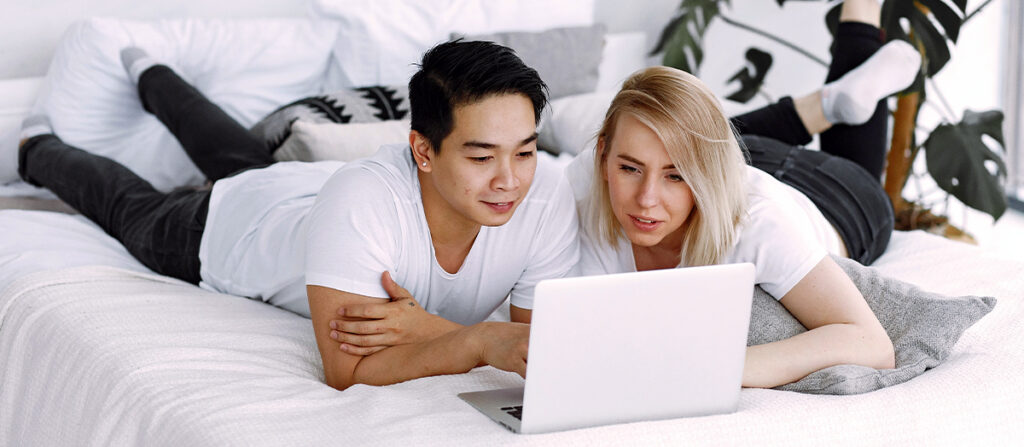 couple surfing the internet on a bed